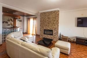 a living room with a white couch and a fireplace at Vivenda Esgravina in Sesimbra