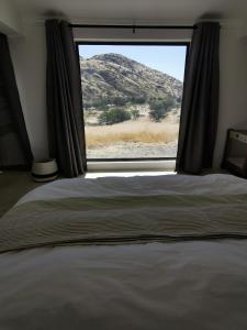 a bedroom with a window with a view of a mountain at Achab Eco cabin in Usakos