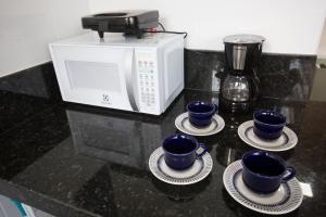 three blue cups on plates next to a microwave at Locking's Lourdes 10 in Belo Horizonte