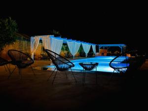 a group of chairs in front of a pool at night at Family Villages Santorini in Vlychada Beach