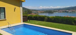 una piscina junto a una casa con vistas al río en Casa Salinas do Ullo con piscina, en Vilaboa