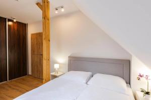 a bedroom with a white bed and a wooden pole at VacationClub - Rezydencja Karkonoska Apartament 10 in Karpacz