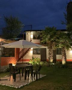 - une table et des chaises avec un parasol en face d'une maison dans l'établissement Jo´s Place, à Huaraz