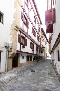 a building with red and white windows on a street at Pensión Txoko Goxoa in Hondarribia