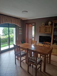 comedor con mesa de madera y sillas en Casa Salinas do Ullo con piscina, en Vilaboa