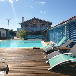 una piscina con sedie a sdraio e una casa di La Maison Mosaic Medoc - Gîtes a Gaillan-en-Médoc