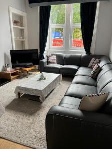 a living room with a black leather couch and a coffee table at Murrayfield apartment in Edinburgh