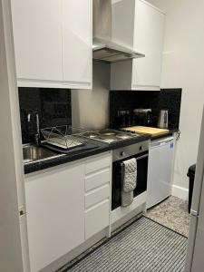 cocina con armarios blancos, fregadero y fogones en Murrayfield apartment en Edimburgo