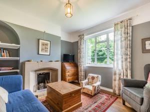a living room with a fireplace and a chair at Chasewoods Farm Cottage in Ogbourne Saint George
