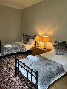 two beds in a room with two lamps and a rug at Murrayfield apartment in Edinburgh