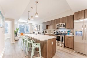 a kitchen with wooden cabinets and a kitchen island with stools at Upscale Modern Apts - Free Parking, Fast WiFi, Courtyard in Austin