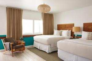 a hotel room with two beds and a chair at Cambria Beach Lodge in Cambria