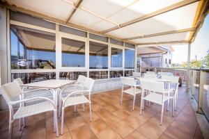 a patio with white tables and chairs on a balcony at Hotel Paraimo in A Lanzada