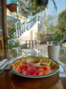 a plate of fruit and a cup of tea on a table at Hotel Rabin Itzam in Lanquín