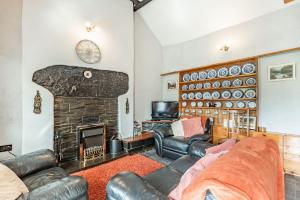 uma sala de estar com mobiliário de couro e uma lareira em Henrhiw Bach em Dolwyddelan