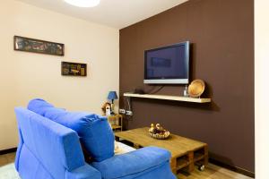La Higuera ( Casa Rural de Gredos ) في Villarejo del Valle: غرفة معيشة مع كرسي أزرق وتلفزيون