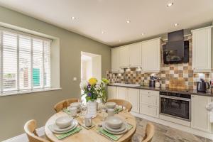 eine Küche mit einem Holztisch und Stühlen sowie eine Küche mit weißen Schränken in der Unterkunft Fisher Cottage in Hornsea