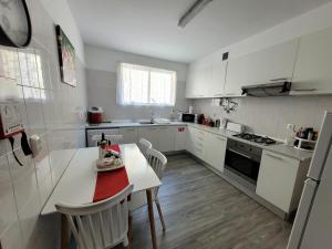 uma cozinha com armários brancos e uma mesa e cadeiras brancas em Casa Alegria em Funchal