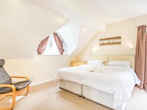 a bedroom with a white bed and a chair at Beeches Studio in Great Witcombe