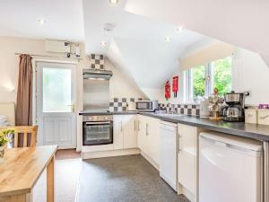 a kitchen with white cabinets and a table at Beeches Studio in Great Witcombe