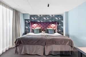 een slaapkamer met een groot bed met een paars hoofdeinde bij Best Western Princess Hotel in Norrköping