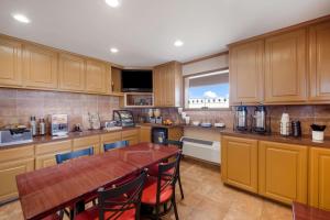 a kitchen with wooden cabinets and a wooden table at SureStay Hotel by Best Western Rockdale in Rockdale