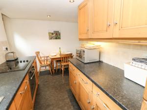 a kitchen with wooden cabinets and a table with a microwave at 89 High Street in Kirkby Stephen