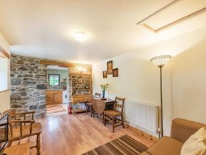 a living room with a table and chairs and a stone wall at Cilwen Fach in Abernant