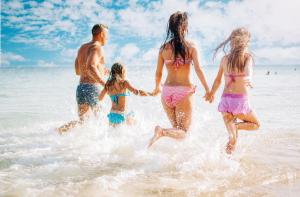 a family running in the water on the beach at Cristian Apartaments in Capo Vaticano