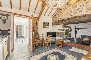 a kitchen and living room with a table and a fireplace at Y Becws in Llanbedr