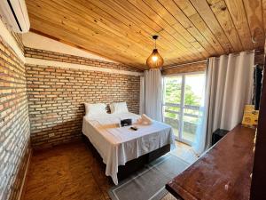 a bedroom with a bed and a brick wall at Villa Flecheiras in Flecheiras