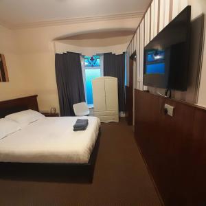 a hotel room with a bed and a flat screen tv at Merginn Guest House in Blackpool