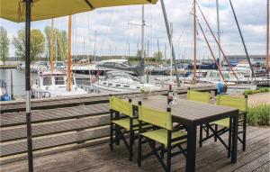 a wooden table and chairs on a dock with boats at Bungalowpark Wijdland-aak in Bunschoten