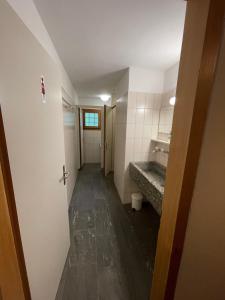 - un couloir d'une salle de bains pourvue d'un lavabo et d'un miroir dans l'établissement Gasthaus Beverin, à Fardün