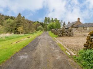 an empty road in front of a stone wall at Gallow Law Cottage in Greenhaugh