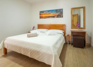 a bedroom with a large white bed and a mirror at Villa Kalinić in Milna