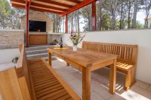 patio z drewnianym stołem i ławkami w obiekcie Villa Kalinić w mieście Milna