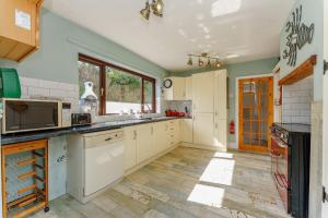 a kitchen with white cabinets and a wooden floor at Rumson House in Trearddur