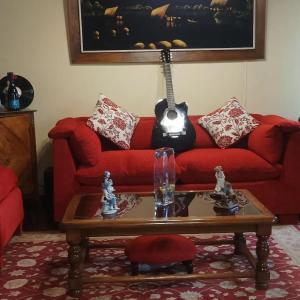 sala de estar con sofá rojo y guitarra en La Ruta del Jazz, en Santa Cruz