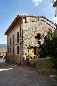 La Higuera ( Casa Rural de Gredos ) في Villarejo del Valle: مبنى حجري قديم امامه طاولة