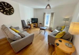 a living room with two couches and a clock on the wall at The Knots-Spacious 3 bedroom apartment in Bridport in Bridport