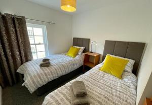 una camera con 2 letti con cuscini gialli e finestra di The Knots-Spacious 3 bedroom apartment in Bridport a Bridport