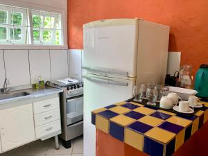 a kitchen with a white refrigerator and a tile floor at Waimea Flats Maresias in Maresias