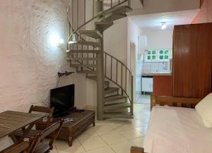 a living room with a spiral staircase and a kitchen at Waimea Flats Maresias in Maresias