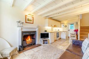a living room with a fireplace and a kitchen at Lavender Cottage in Askrigg