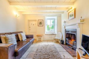 a living room with a leather couch and a fireplace at Lavender Cottage in Askrigg