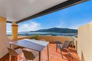 a balcony with a table and chairs and the ocean at Magnificence At Airlie in Airlie Beach