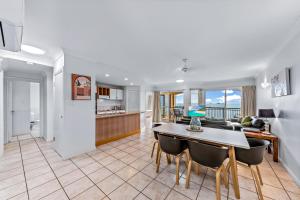 a kitchen and living room with a table and chairs at Magnificence At Airlie in Airlie Beach