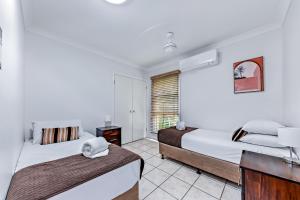 a bedroom with two beds and a window at Magnificence At Airlie in Airlie Beach