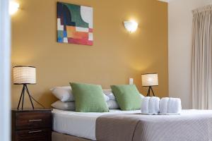a bedroom with a bed with two lamps on it at Magnificence At Airlie in Airlie Beach